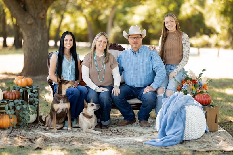 The Goodins sitting outdoors on an autumn afternoon with their two dogs and a pile of pumpkins